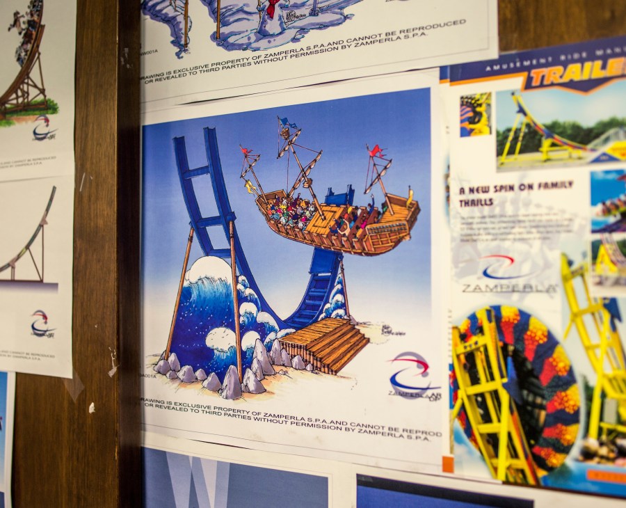 Design sketches and concept art for Zamperla amusement park rides displayed on office walls.