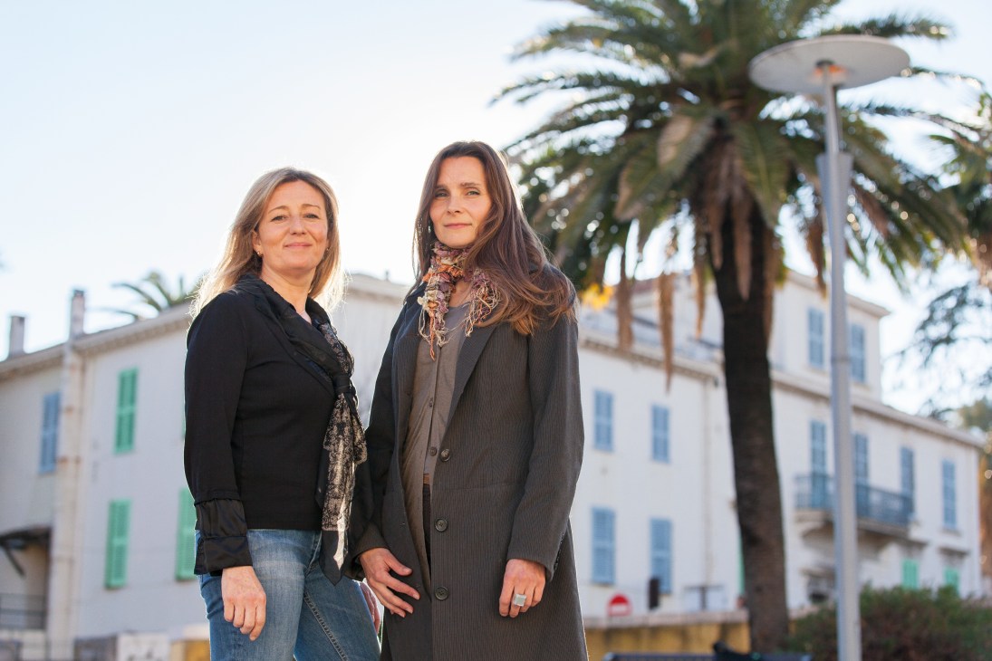 Carole Biancalana and Armelle Janody of Fleurs d'Exceptions du Pays de Grasse stand outdoors with palm trees and French architecture behind them.