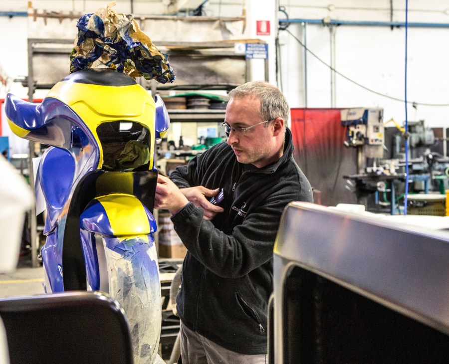 Worker inspects a blue and yellow MotoCoaster seat in the Zamperla factory.