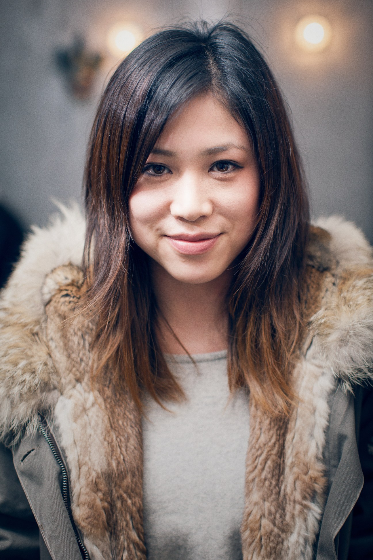 Satoe Tanaka, a Japanese trainee perfumer at Robertet, smiles at the camera wearing a beige fur-lined jacket.