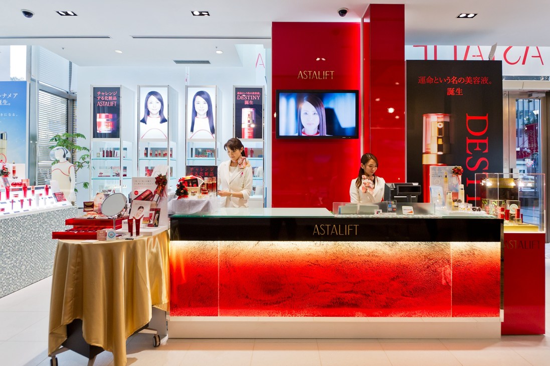 Astalift beauty counter with red branding, display shelves, and staff in Fujifilm's Tokyo headquarters.