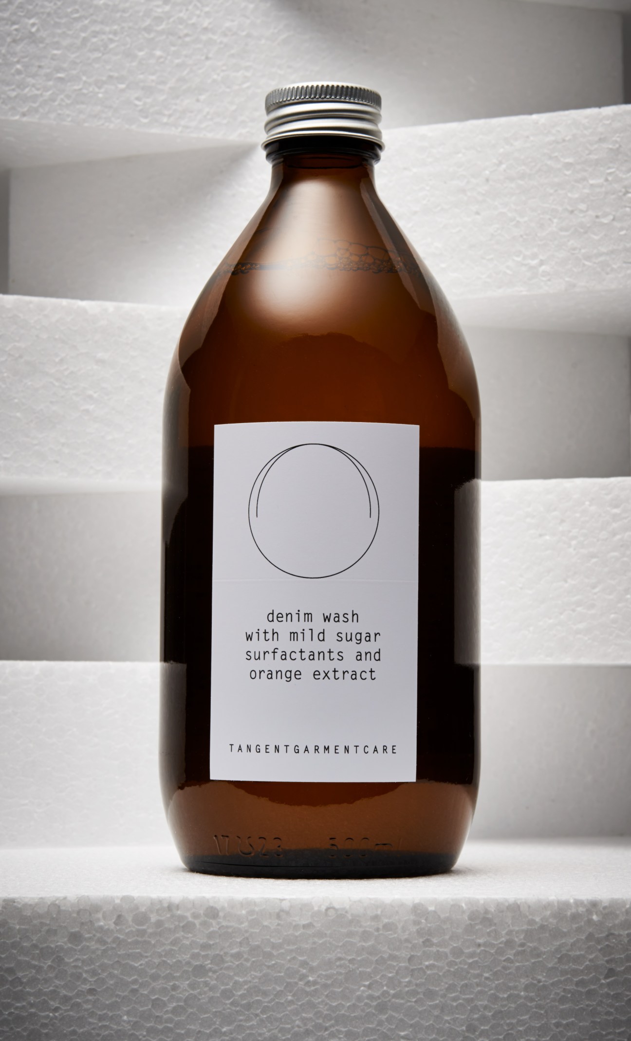 Tangent GC denim wash bottle with label describing mild sugar surfactants and orange extract.