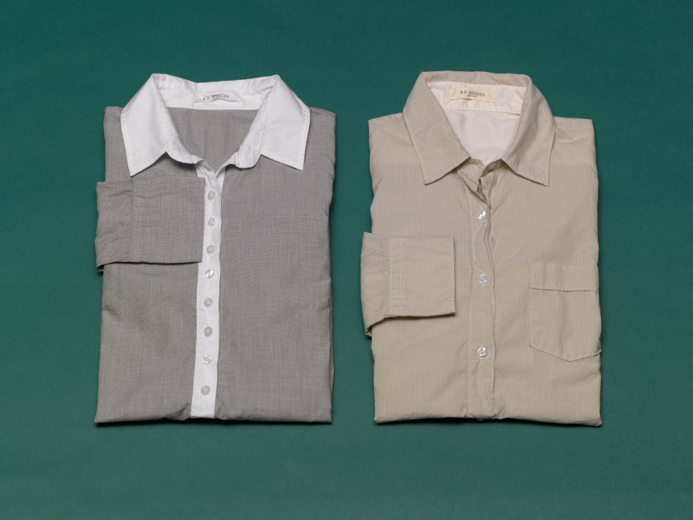 Two folded BD Baggies women's button-down shirts in neutral tones against a teal background.