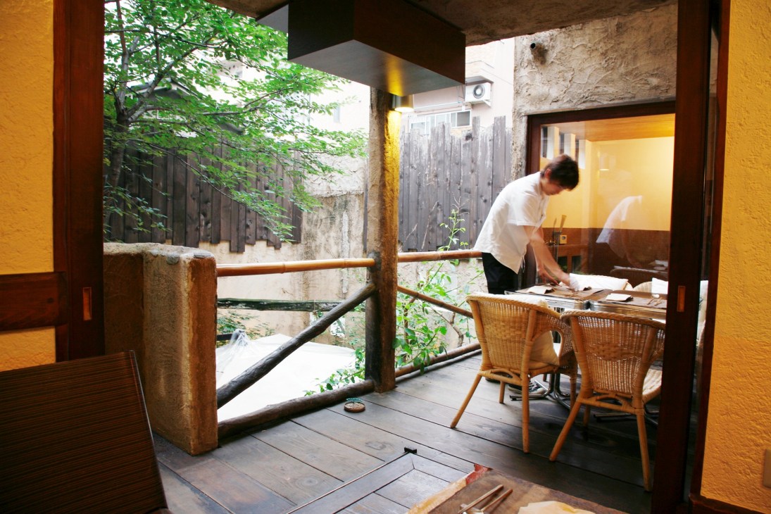 Staff member working at a counter inside Bissori restaurant with courtyard seating visible through open doors.