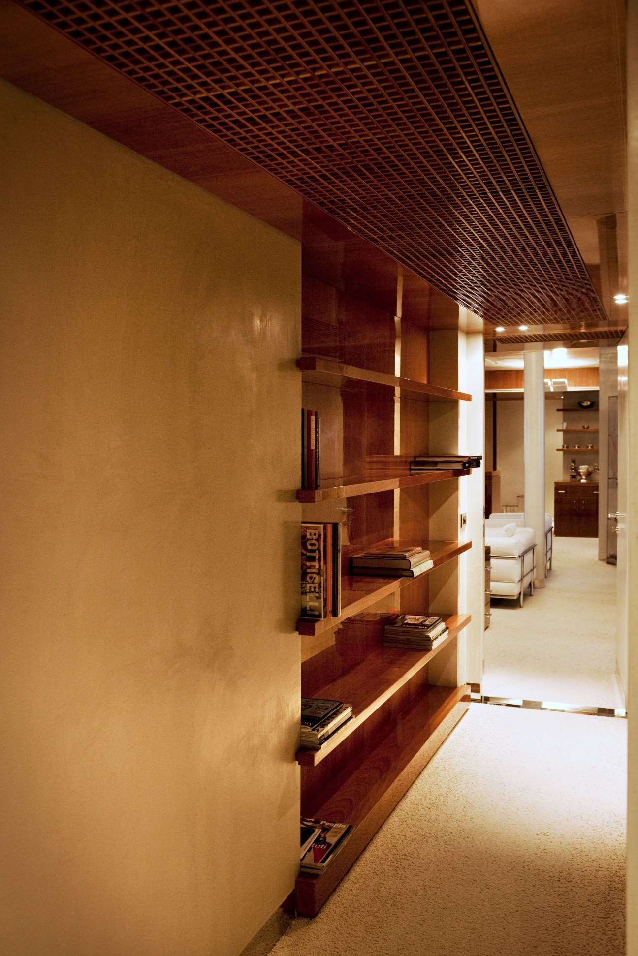 Low-ceilinged corridor with mahogany cabinetry and lattice ceiling evoking a ship's passageway.
