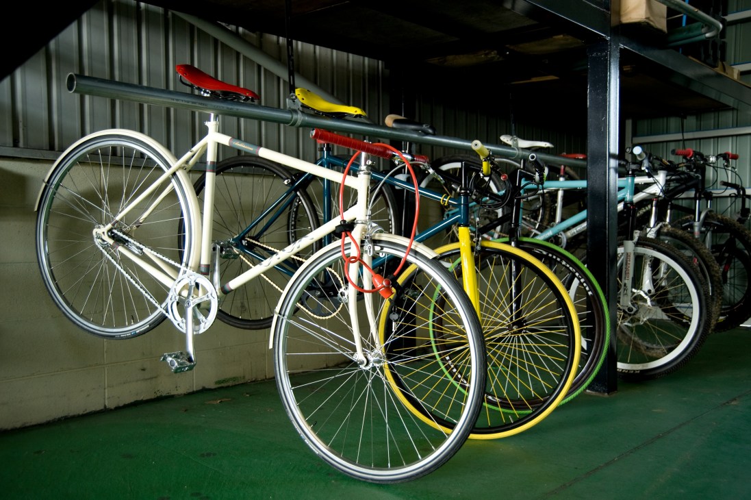 Colourful customisable Funriki bicycles displayed in a warehouse, showing white, yellow, and black frames with varied components.