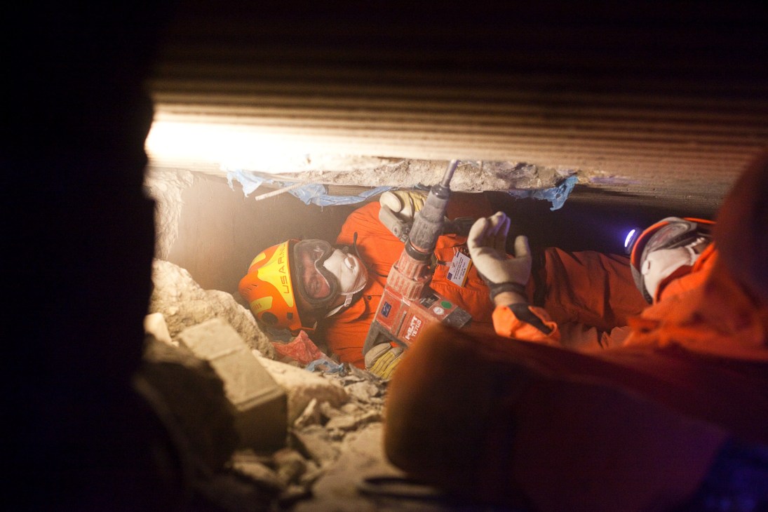 Rescue workers in orange gear conduct earthquake training inside a rubble-filled tunnel in Wesel, Germany.