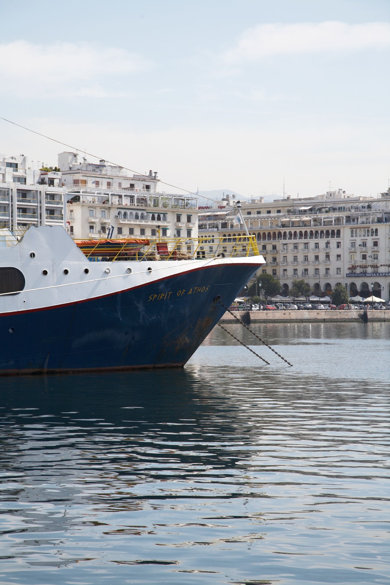 Ferry ship docked at Thessaloniki harbour with waterfront buildings and promenade in background