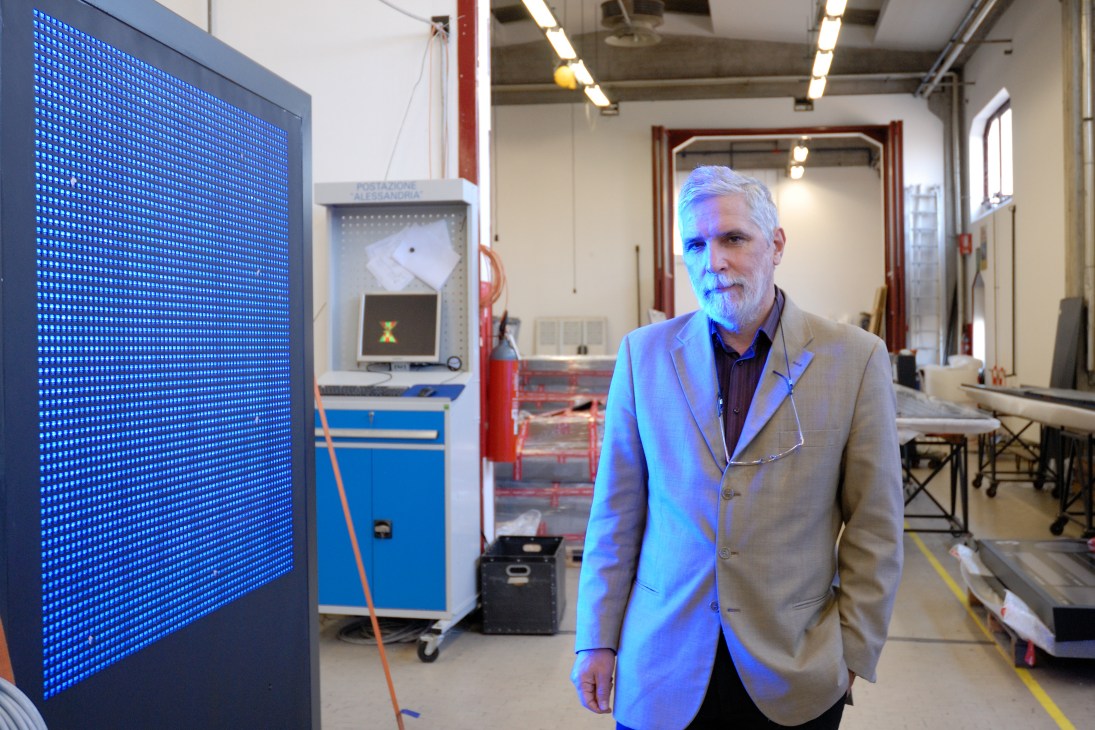 Carlo Concina, director of production, stands next to a blue LED display panel in Solari's manufacturing facility.