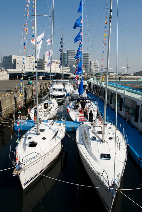 White sailing yachts with colorful flags moored at a marina during the Japan International Boat Show in Yokohama.
