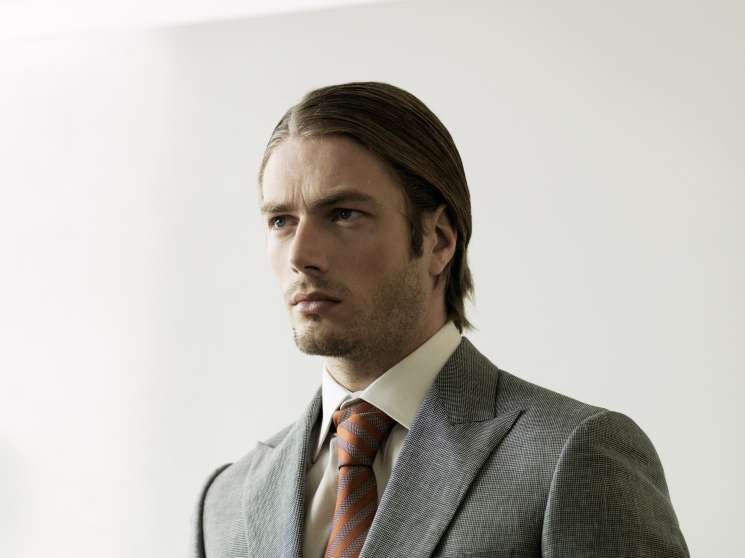Man wearing wool/linen suit by Kilgour, cotton shirt by Hackett, and silk tie by Gieves & Hawkes.
