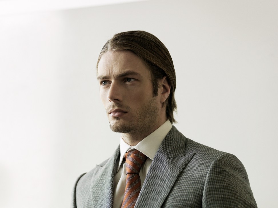 Man wearing wool/linen suit by Kilgour, cotton shirt by Hackett, and silk tie by Gieves & Hawkes.