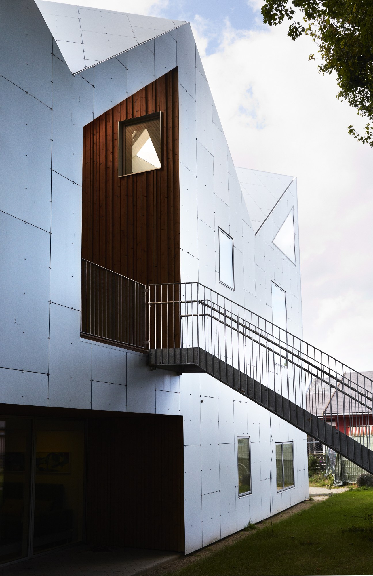 Center for Cancer and Health exterior showing aluminium-clad façade with pitched roof design and wooden entrance frame.