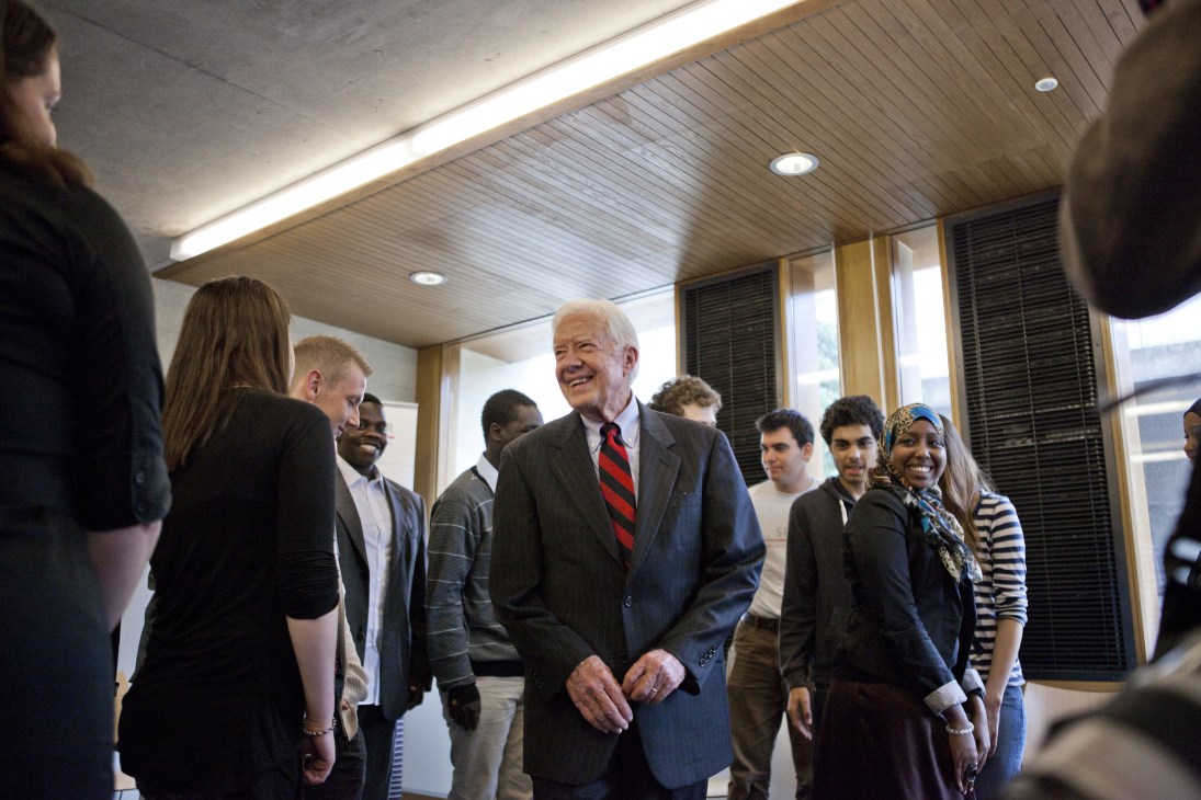 Former US president Jimmy Carter smiles while speaking with young trainees at a London homeless charity.