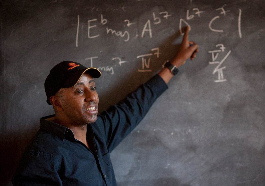 Henock Temesgen points to musical notation written on a chalkboard at his African Jazz School.