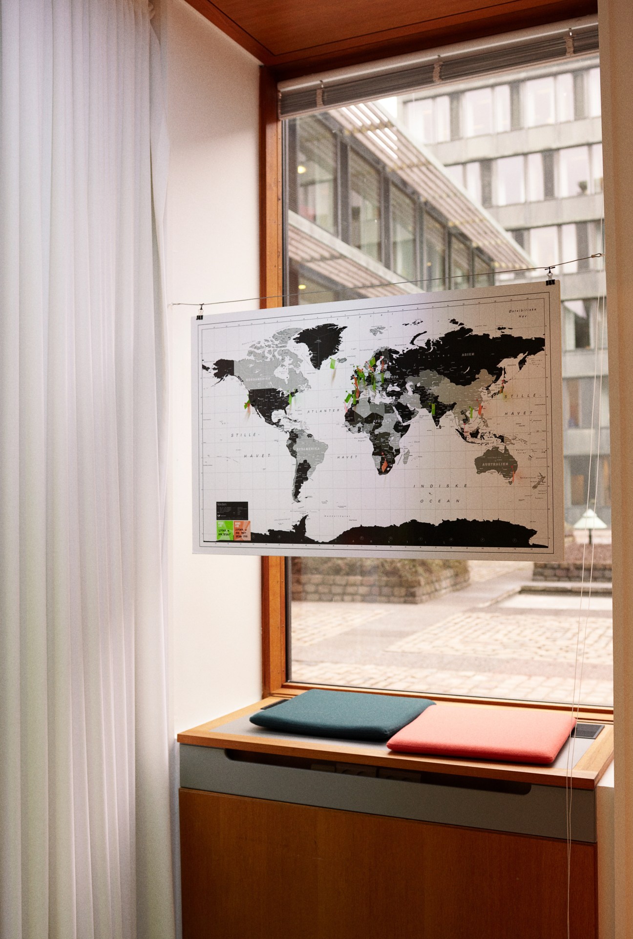A world map with colored markers indicating Mindlab's global network locations displayed in an office window.