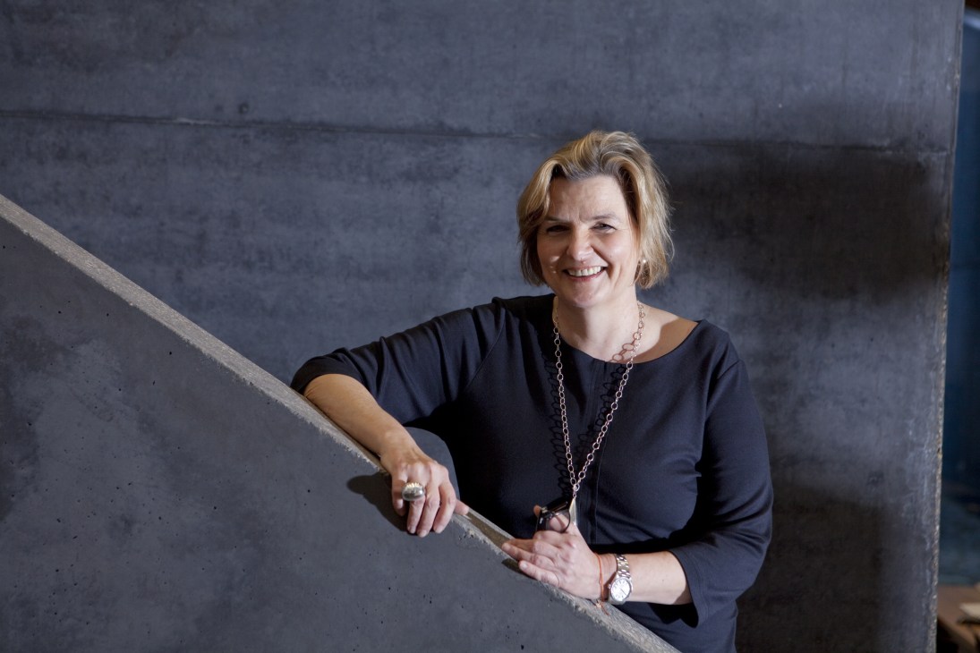 Uta Grosenick, co-founder of Distanz, smiles while leaning against a concrete wall.