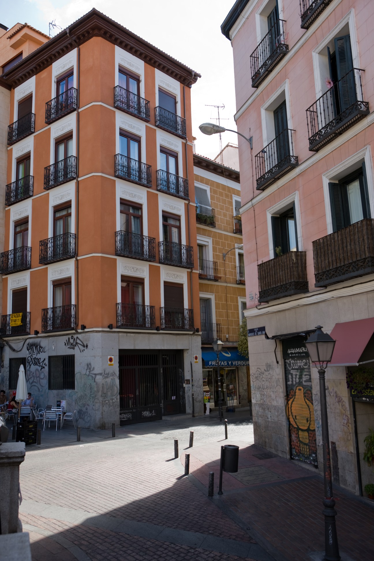 Colorful Bourbon-era apartment buildings with balconies lining a Madrid street in Malasaña neighborhood.