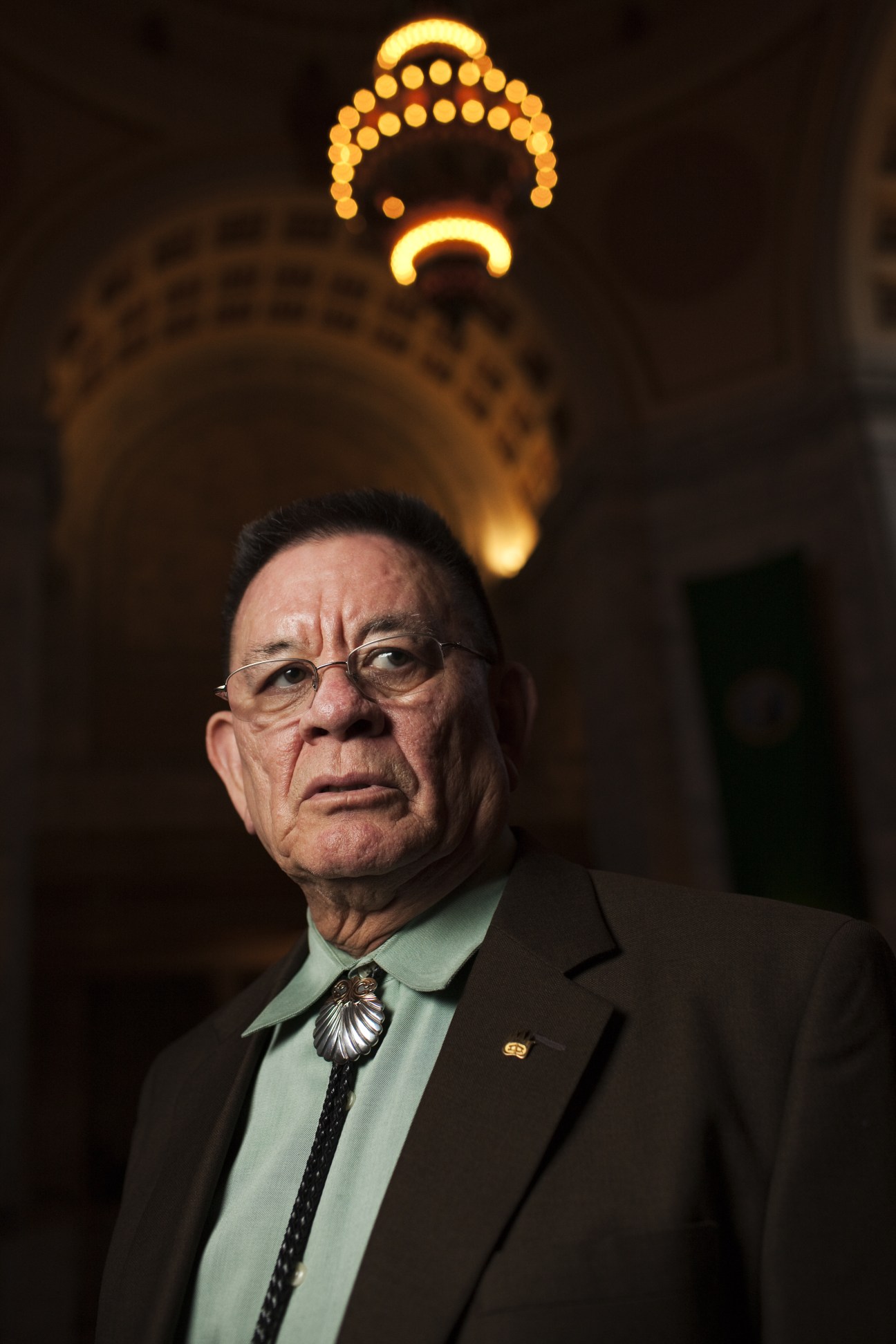 John McCoy, Tulalip tribal leader, poses under illuminated decorative lighting.