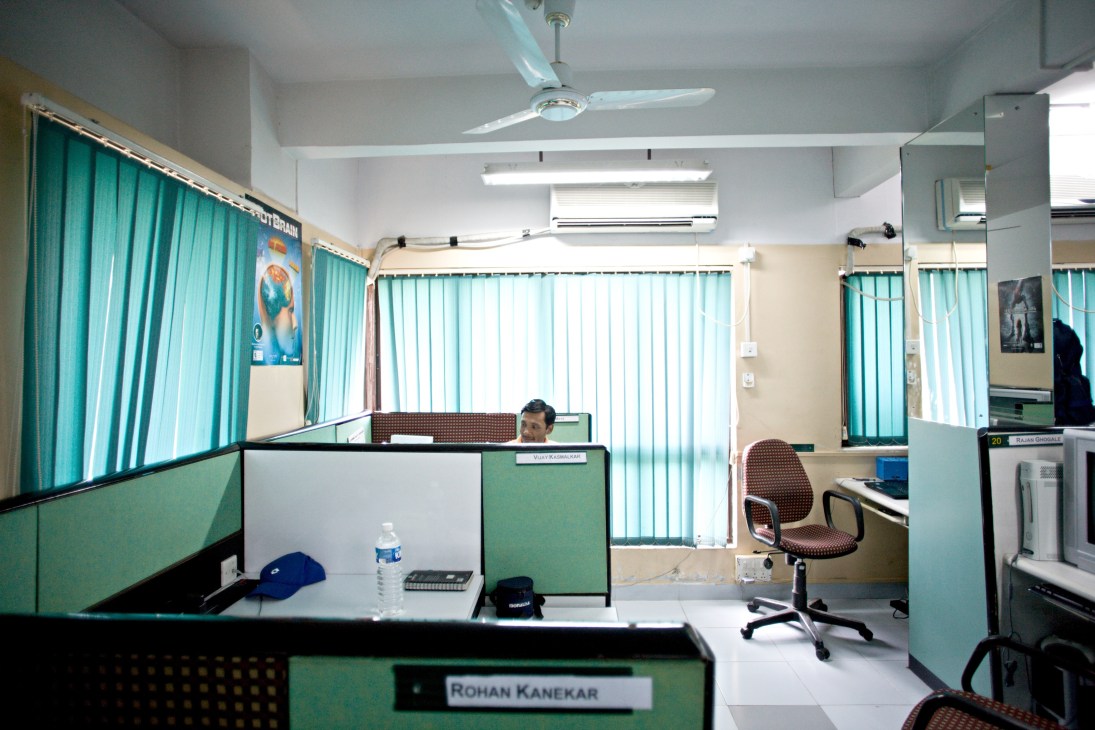 Video game tester working at a desk in an office cubicle at SQS India in Pune.