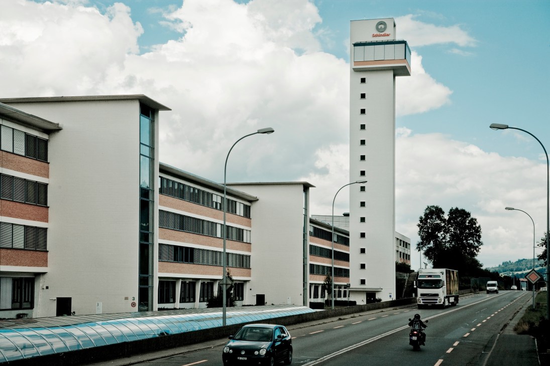 Schindler headquarters in Ebikon, Switzerland, featuring modern white buildings with brick accents and a tall tower structure.