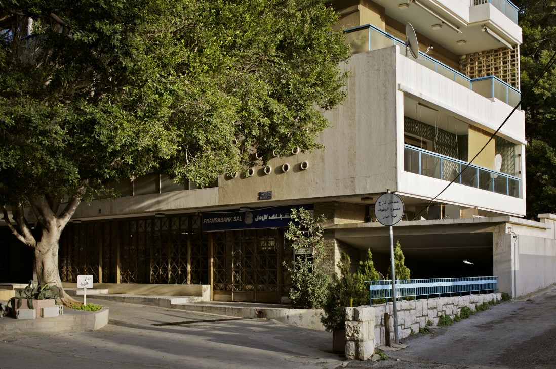 Modern concrete apartment building with large tree and closed storefront on Rue Ashrafieh in Beirut.