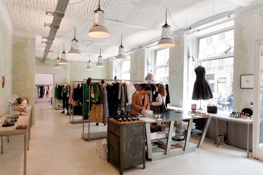 Interior of Song boutique showing clothing racks, pendant lights, and owner Myung-Il Song at the counter.