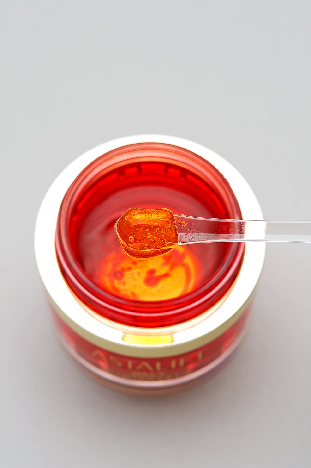 Astalift Jelly Aquarysta skincare product in red jar with spoon showing gel texture.
