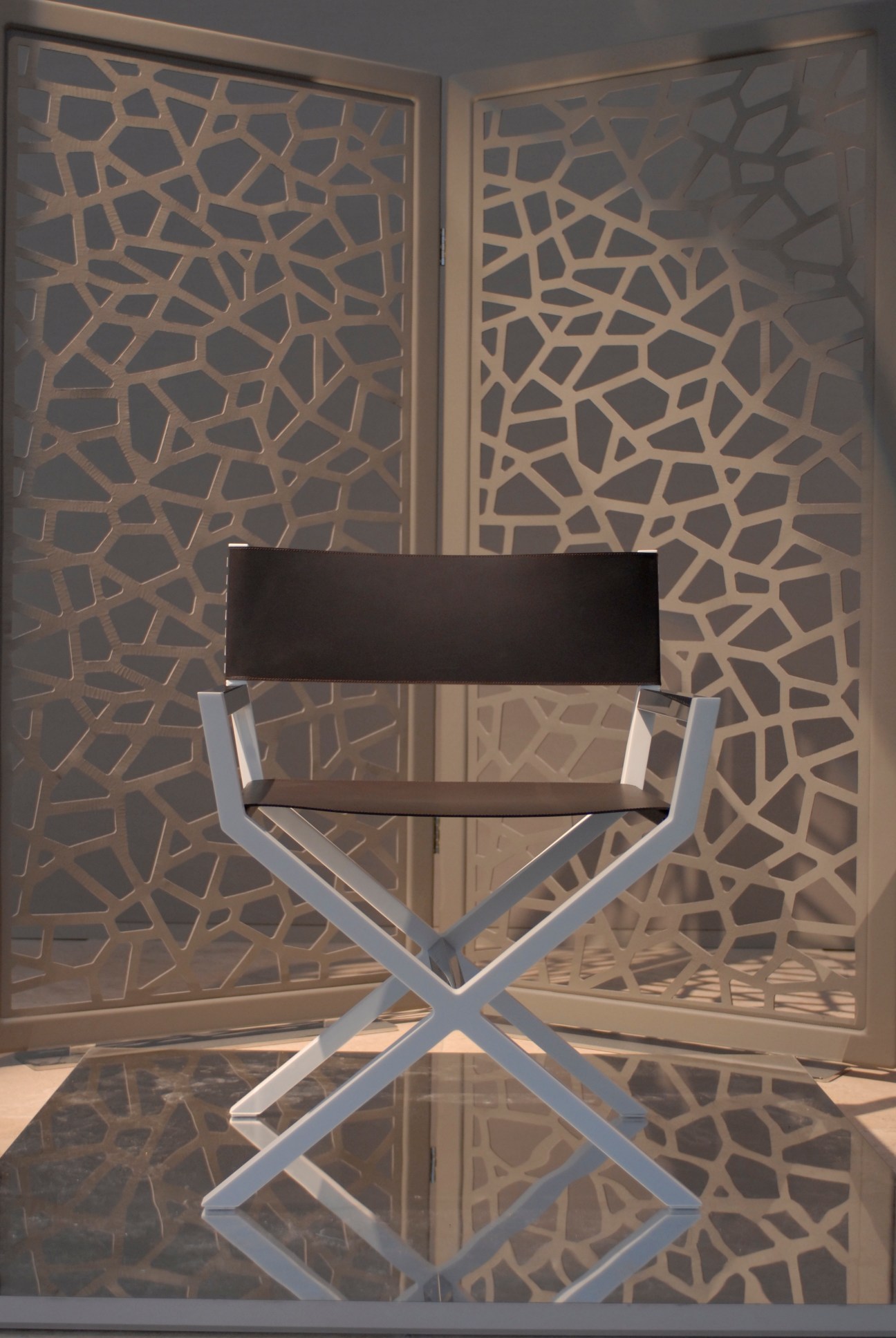 Helleu director's chair by François Russo for Poltrona Frau with metal X-frame and dark seat against patterned backdrop.