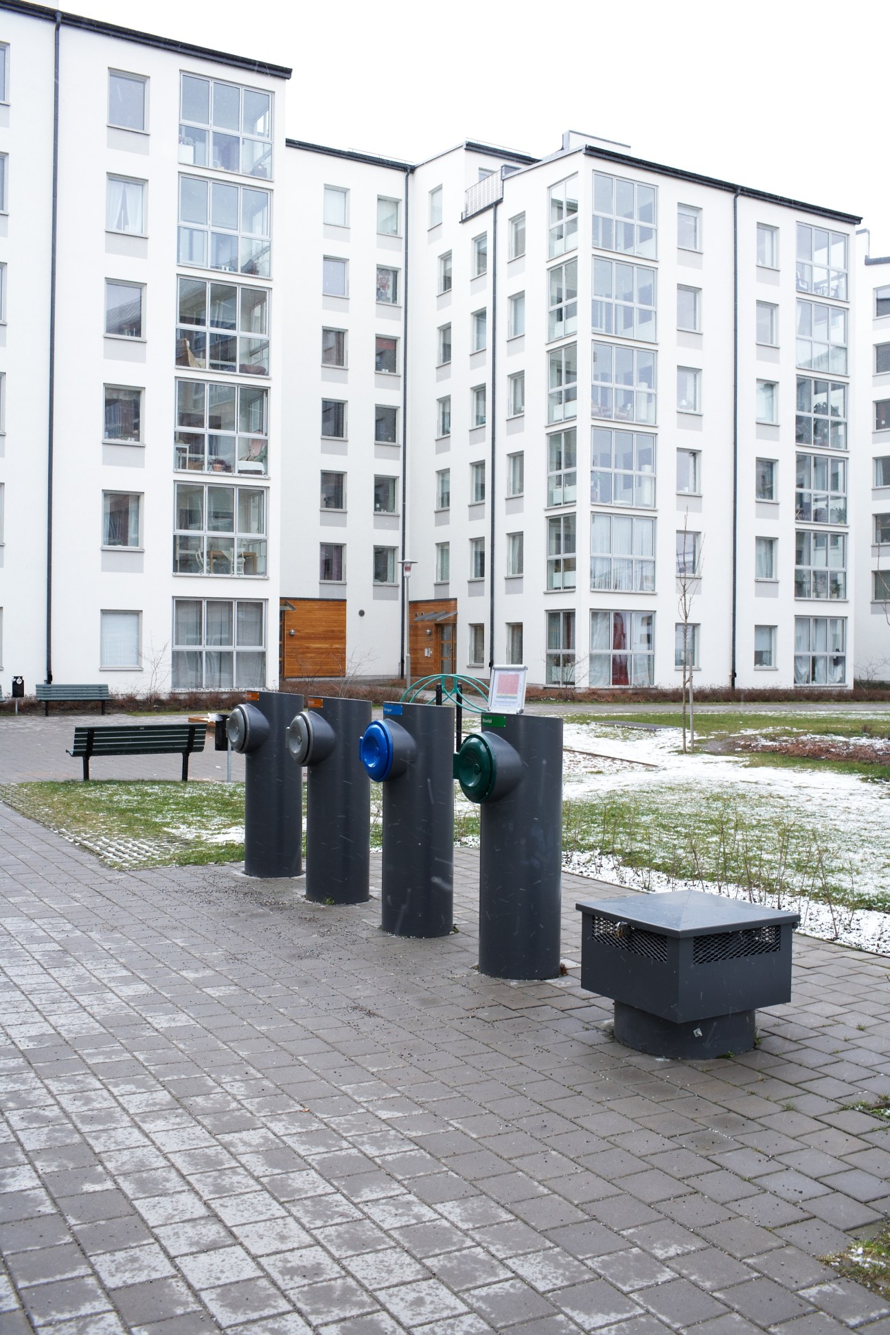 Envac waste collection bins with coloured lids in a Stockholm residential courtyard.