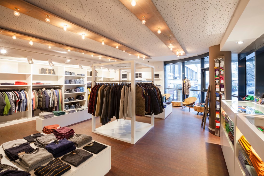 Interior of Uebervart menswear boutique in Frankfurt with white shelving, clothing displays, and wooden flooring.