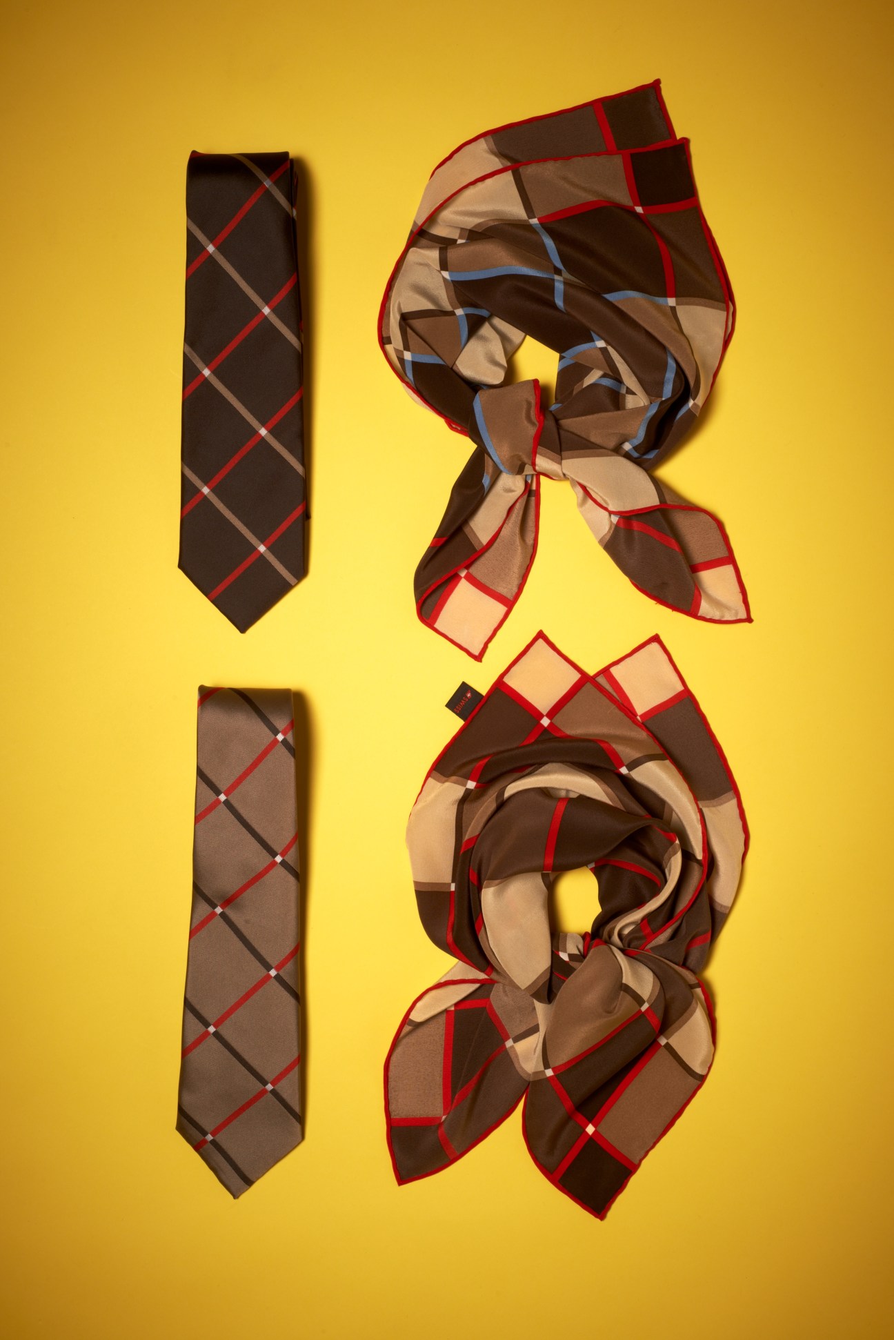 SWISS airline crew accessories including a dark tie with red and gray plaid pattern and two coordinating scarves with matching checked design on yellow background.