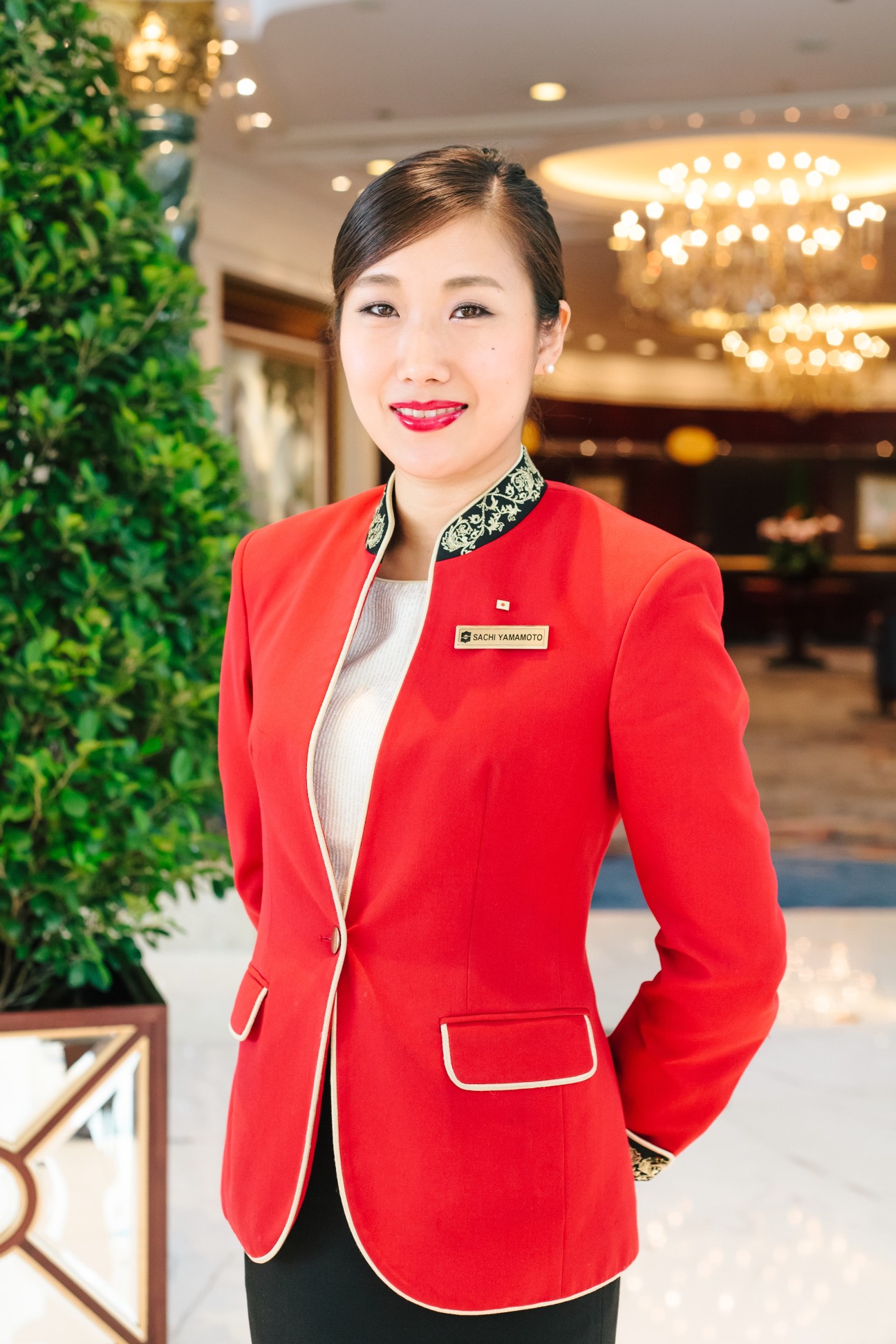 Sachi Yamamoto, Shangri-La Hong Kong check-in assistant, wearing red blazer in hotel lobby.