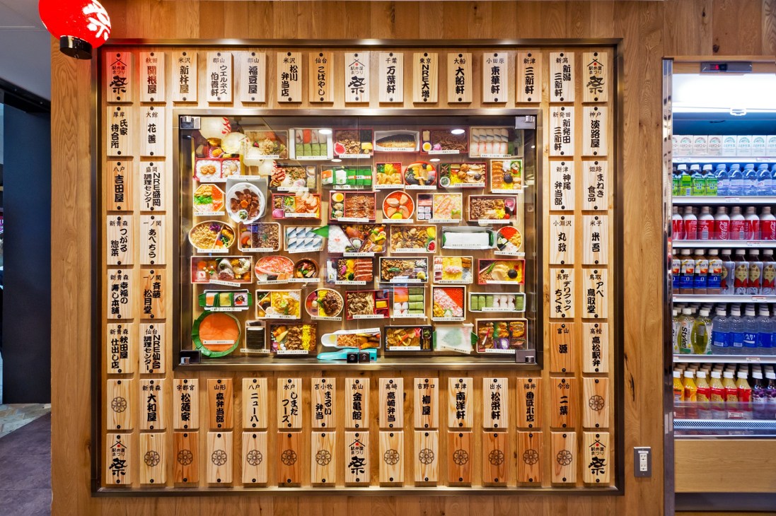 Wooden display wall of bento boxes at Ekibenya Matsuri in Tokyo Station featuring various regional Japanese meal options.