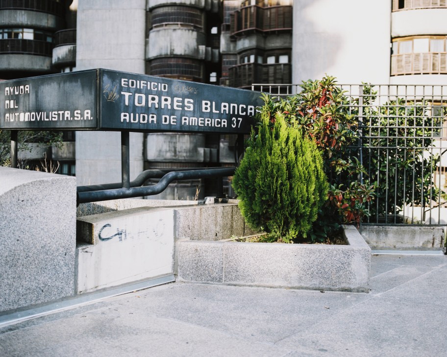 Torres Blancas building entrance sign with modernist architecture and landscaping visible from street level.