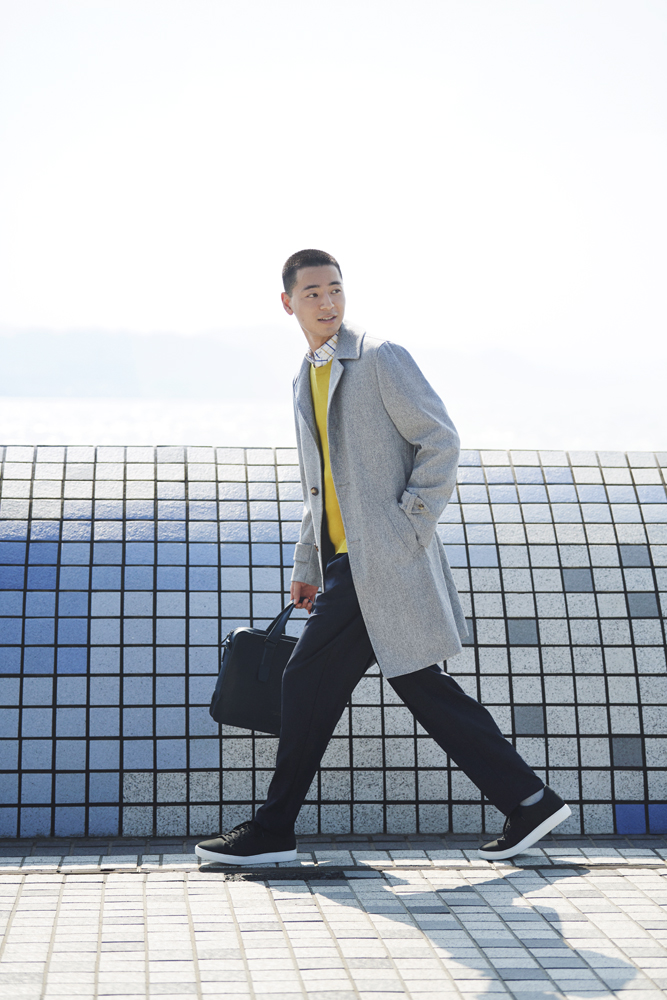 Model wearing minimalist jacket and trousers with designer backpack