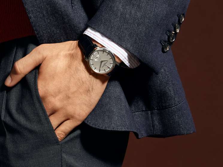 Man in navy blazer with white shirt and grey trousers wearing Vacheron Constantin watch