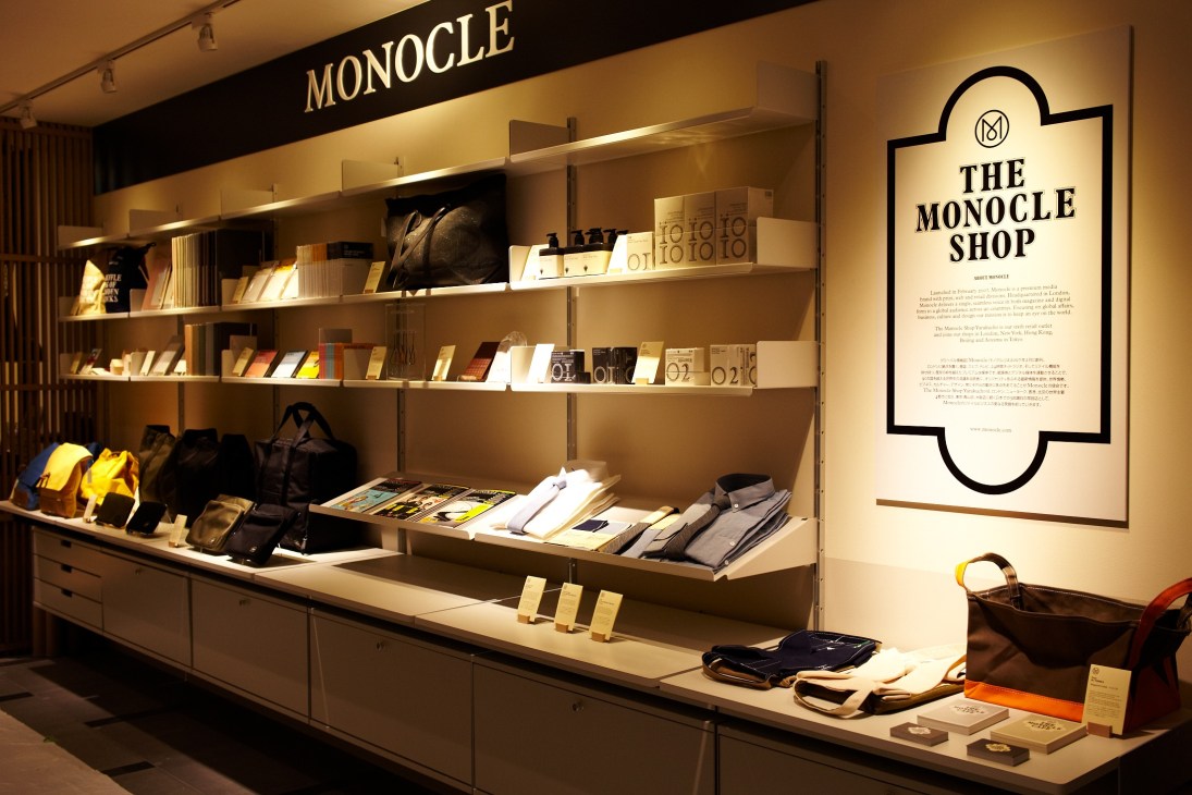 Monocle Shop display featuring Vitsoe shelving with curated accessories, books, and merchandise under warm lighting.