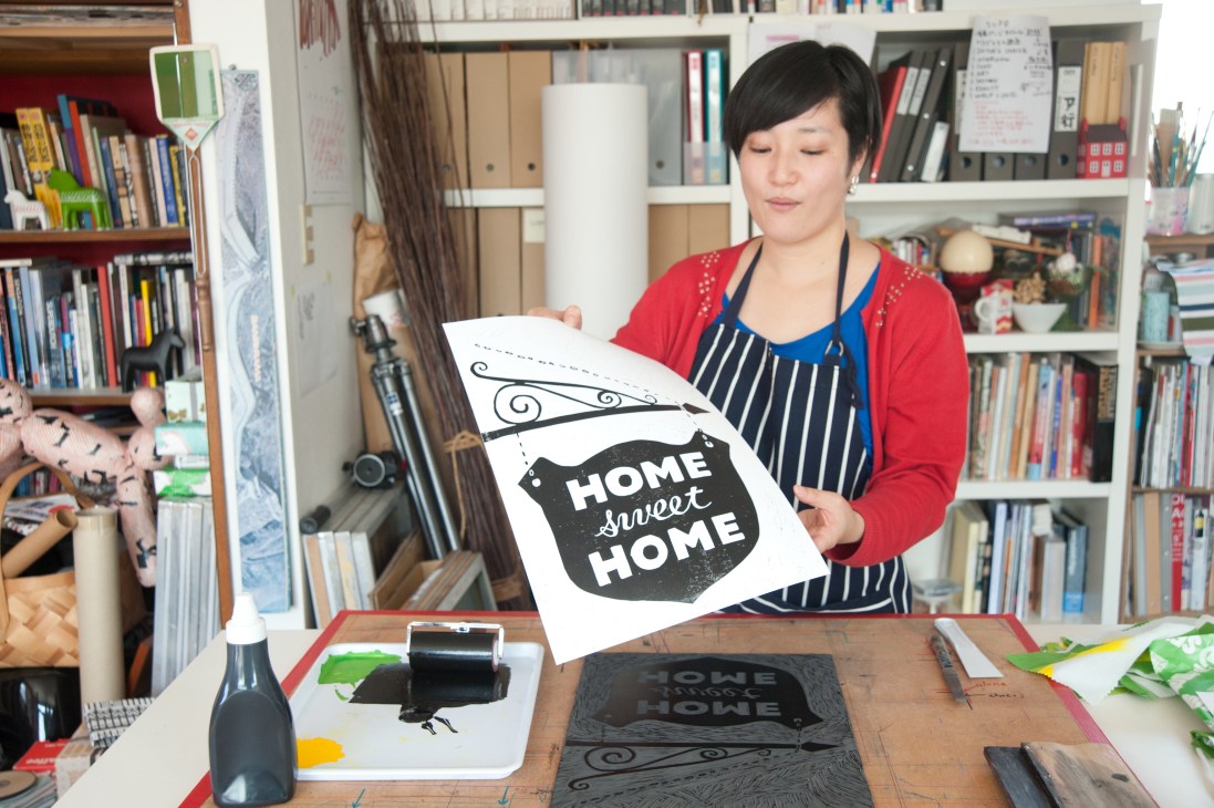 Hiromi Asakura printing an original design with a house-shaped stamp in her studio.
