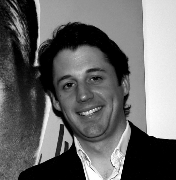 Black and white portrait of Chris Pensa, founder of Love Art London, smiling at the camera.