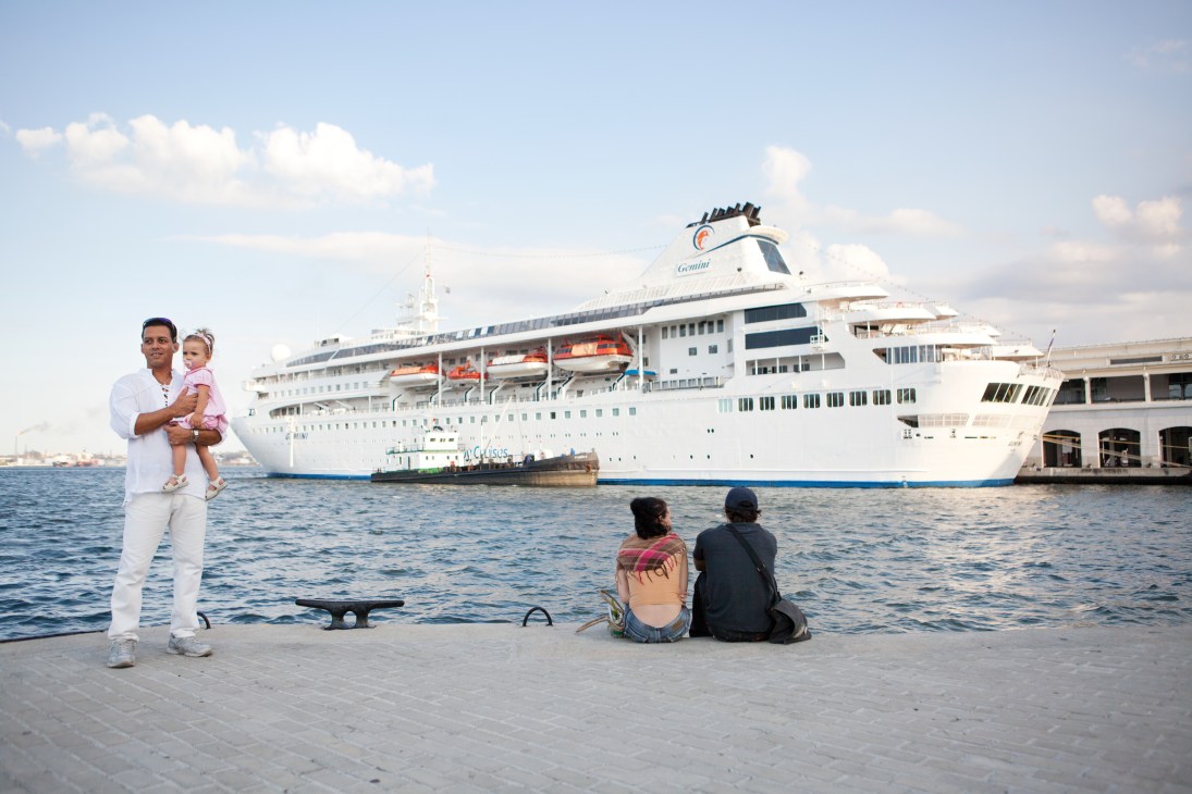 A cruise ship docked in Havana port with people viewing from the waterfront.