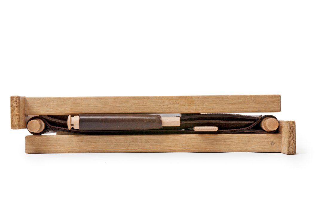 Åke Axelsson's Ferdinand chair in folded position showing oak frame and dark leather seat.