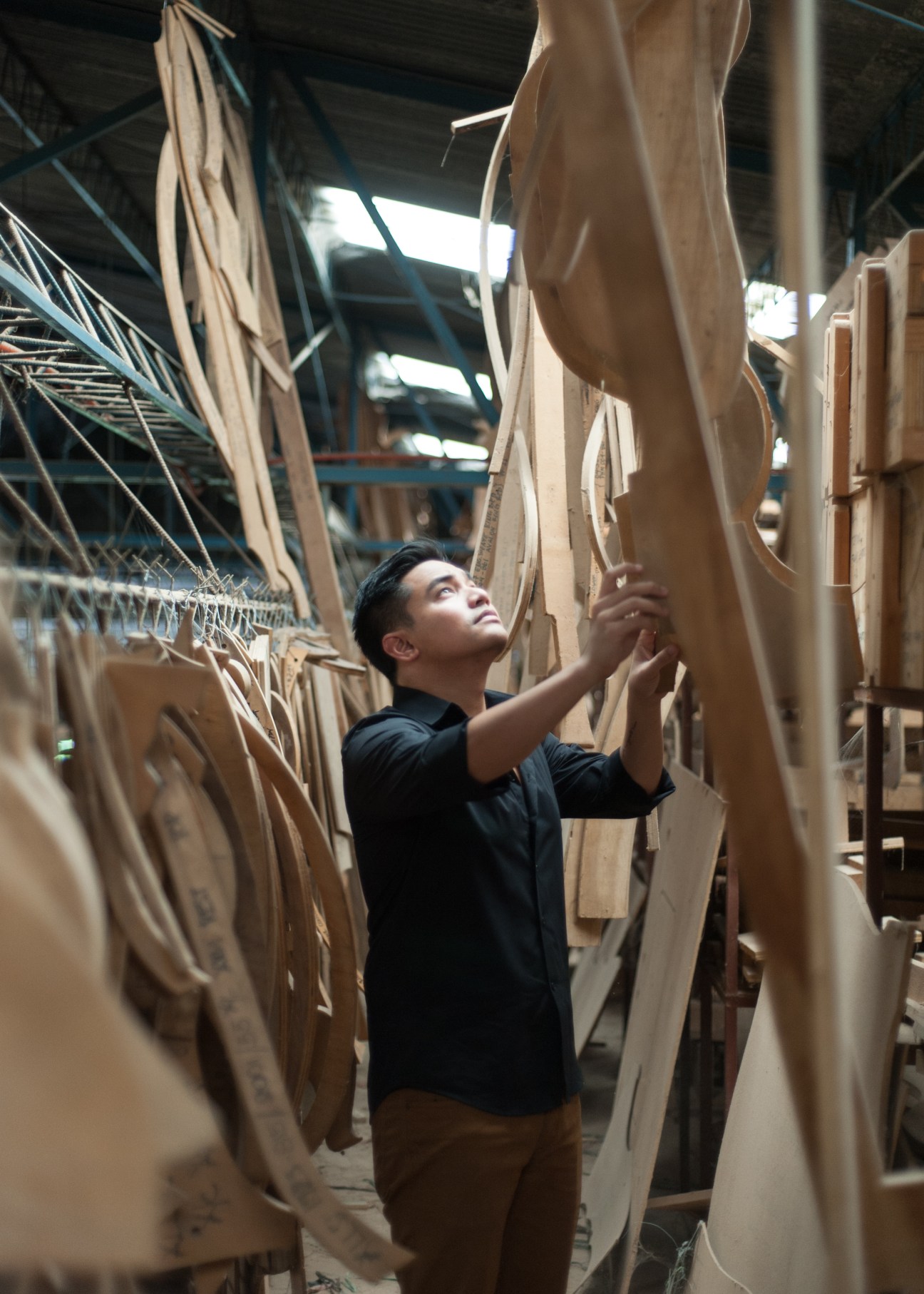 Vito Selma inspects woven fabric strips hanging in a factory workshop.