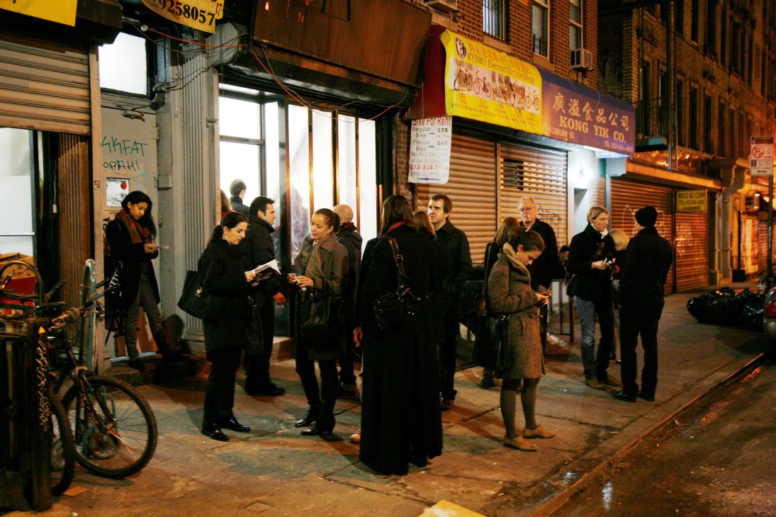 People gathered outside a storefront at night for an exhibition opening at MINI/Goethe-Institut Curatorial Residencies Ludlow 38.