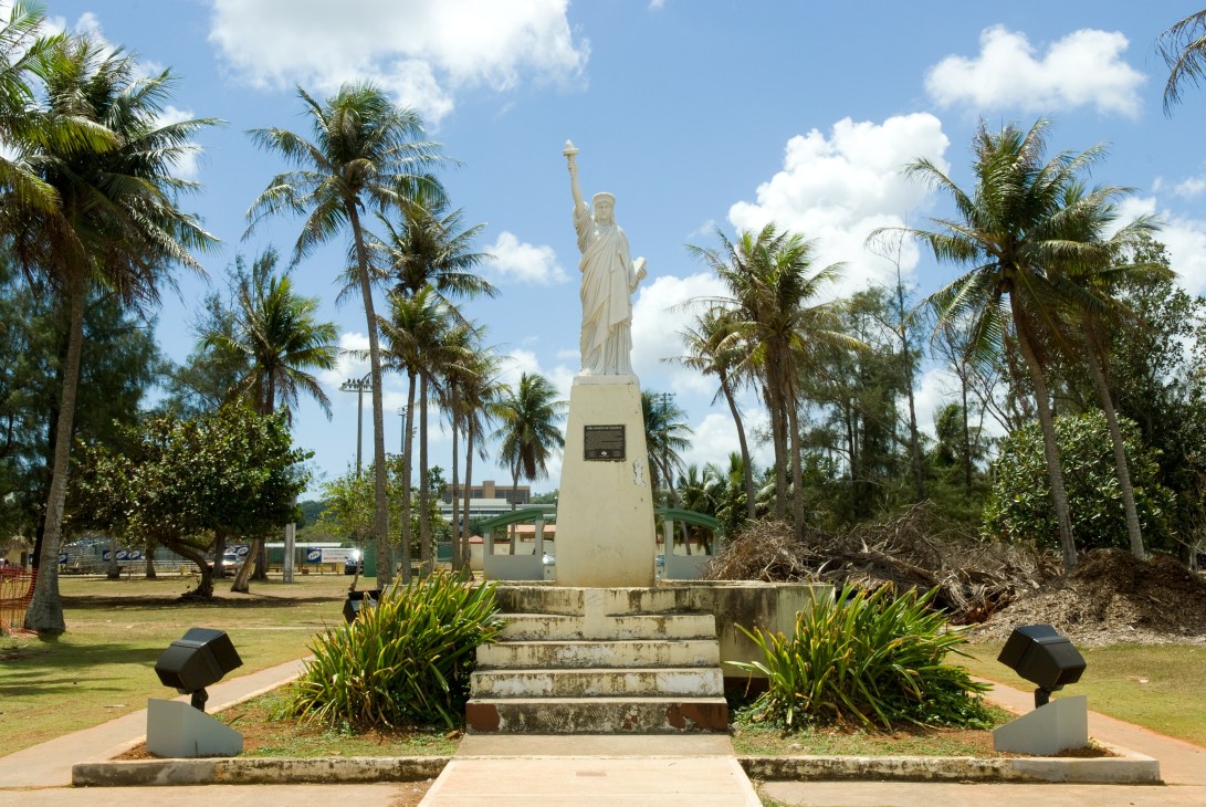 A Statue of Liberty replica surrounded by palm trees at Hagatña harbour in Guam.