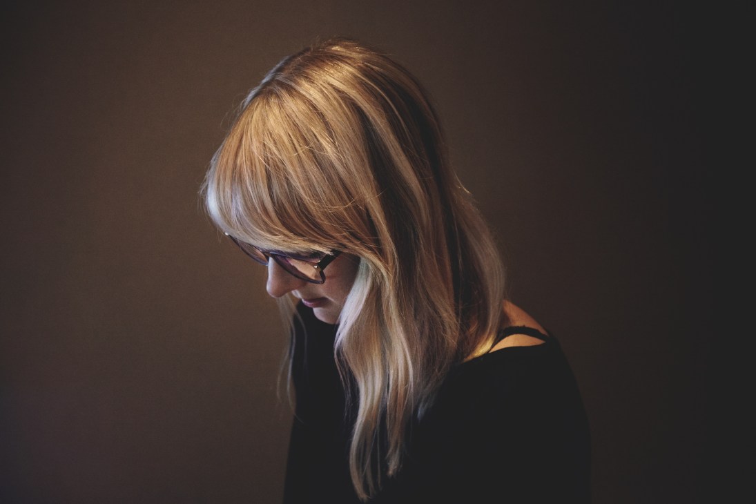 Producer Katie Bilboa in profile wearing glasses, focused on her work in the studio.
