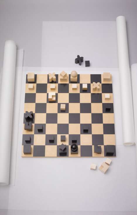 Naef wooden chess set with natural and dark pieces arranged on alternating light and dark squares.