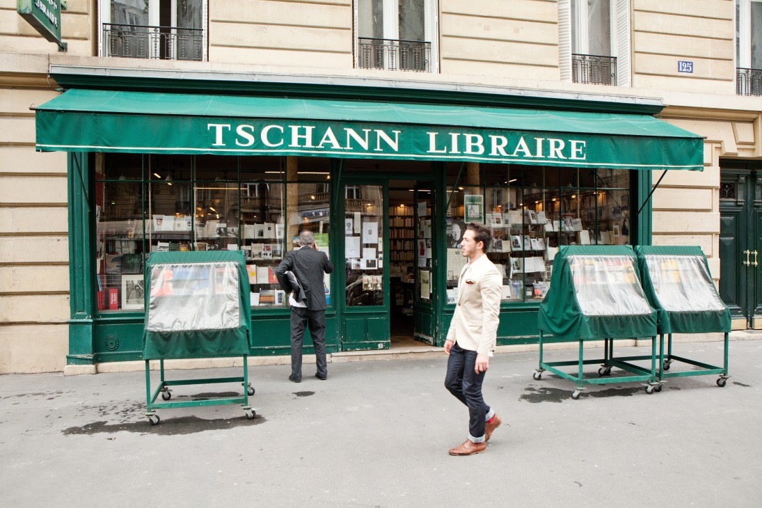 Storefront of Tschann Libraire bookshop on Boulevard du Montparnasse with green awning and window displays.