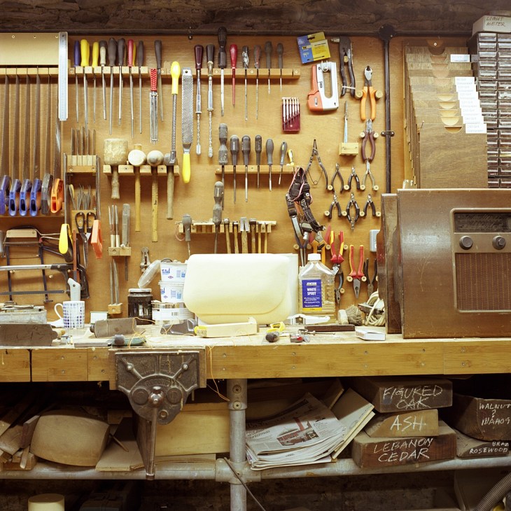Kenneth Grange's workshop with organized hand tools hanging on pegboard above a wooden workbench.