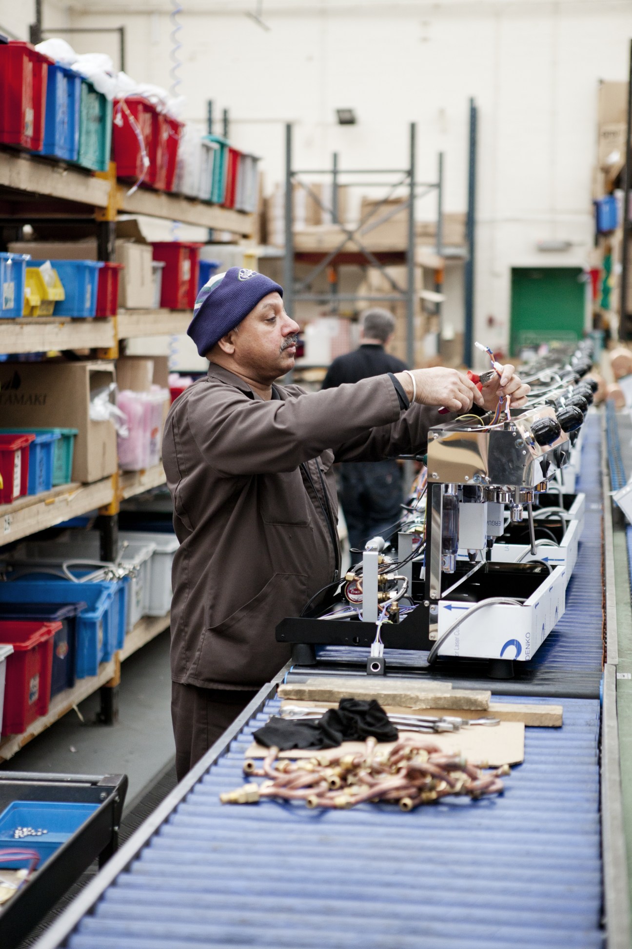 Worker assembling espresso machine components at Fracino factory assembly line in Birmingham.